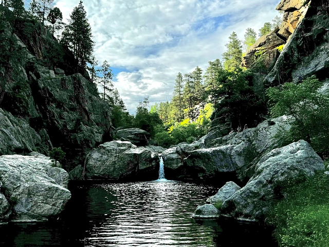 Hippie Hole waterfall and swimming hole in the Black Hills, South Dakota. Surrounded by stone walls and pines.