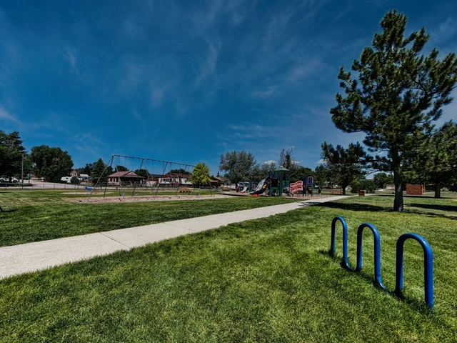The playground at Butler Park in Hot Springs, South Dakota. Bike rack, trees and grass.