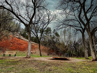 Merry go round, red cliffs, and trees at School St Park in Hot Springs, South Dakota