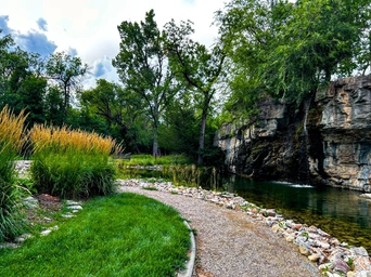 Gravel walking path by Indian Springs tourist attraction in Spearfish, South Dakota. Waterfall and pond on right.