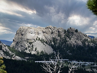 Mount Rushmore from a distance with storm clouds above.