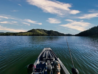 Bonafide fishing kayak on Sheridan Lake in the Black Hills, SD. Pedal kayak with wispy clouds and shoreline in the distance.