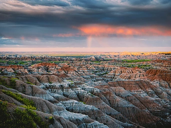 Colorful sands of the Badlands formations with sunset in the distance.