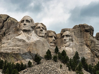 Mount Rushmore with storm clouds in the background.