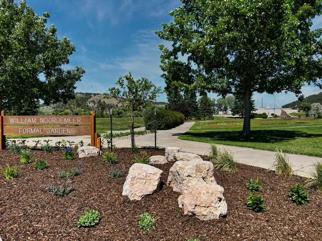 The sign at William Nordemeer Formal Gardens with flowers in the background at Sioux Park.