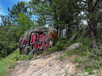 The rock with Hippie Hole spray painted on it at the parking area. Black Hills hike to a natural swimming hole.