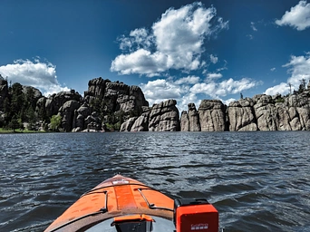Kayaking on Sylvan Lake in Custer State Park with rock outcropping on the horizon.