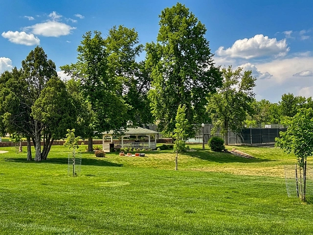 Wilson Park on Mt Rushmore Rd in Rapid City. Towering trees, green lawn, and white gazebo.
