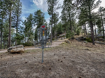 Trail to Big Rock Overlook. Disc golf in foreground. Pine trees and Black Hills scenery.