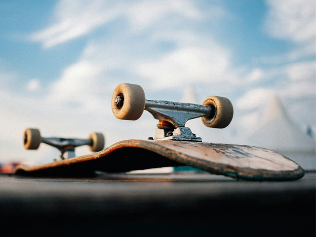 skateboard upside down in skatepark with sky and clouds in the distance.