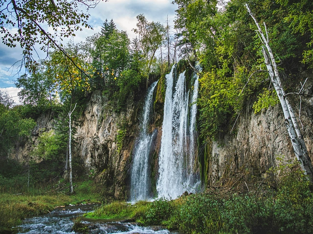 Spearfish Falls in the Black Hills. Waterfall down a cliff with ponderosa pines and blue skies.